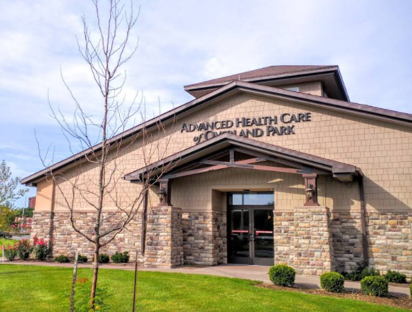 Exterior of Advanced Health Care building with stone entrance and lawn under a cloudy sky