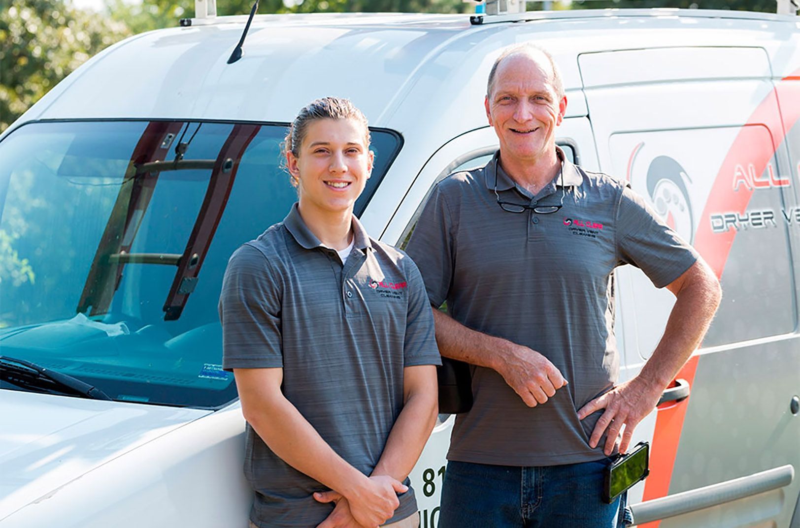 Two men standing in front of a white van, smiling at the camera.