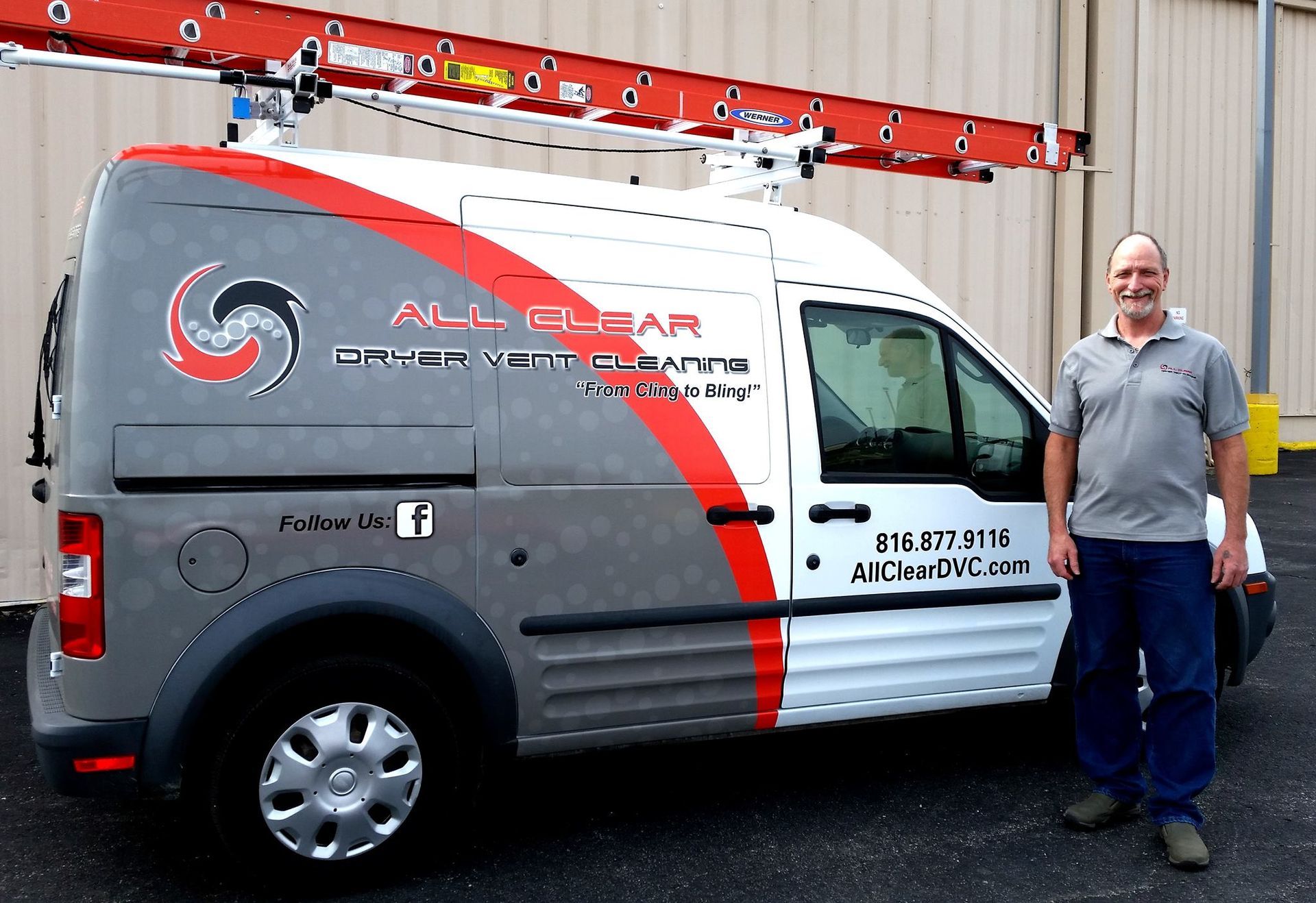 Man standing beside a white and gray service van with red graphics in front of a fire station ladder truck