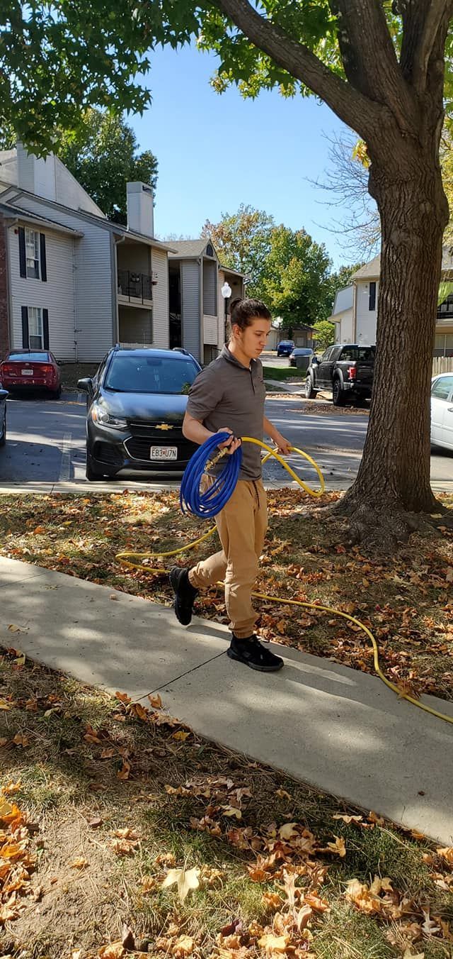 Person walking a dog on a sidewalk in a residential area, with parked cars and apartment buildings nearby.