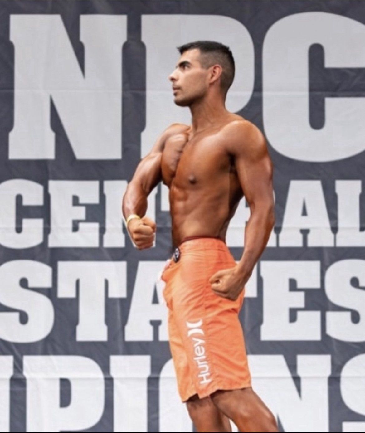 A man in orange hurley shorts stands in front of a npc central states sign