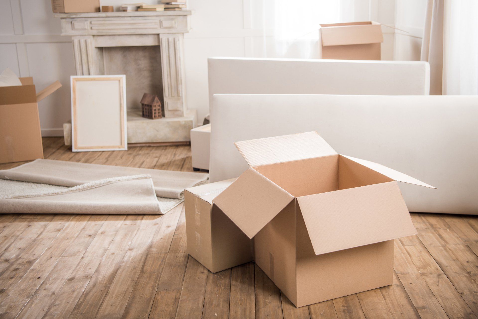 A living room filled with cardboard boxes and a white couch.