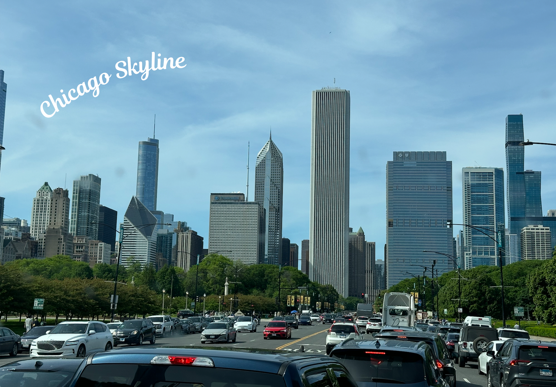 A daytime view of the Chicago skyline featuring the distinctive twisted St. Regis tower, with traffic on a busy road.