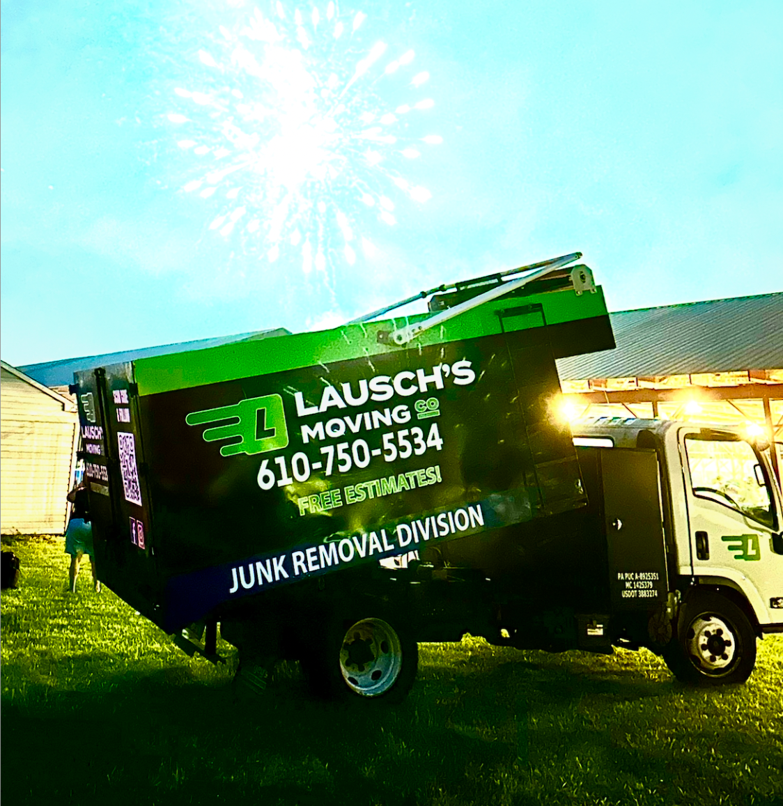 A black and green junk removal truck parked on grass under a digital overlay of fireworks.