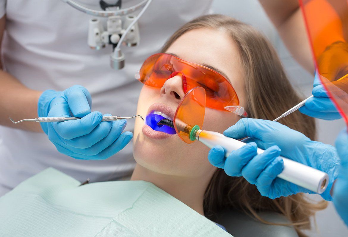 Dentist examining a patient’s teeth with dental tools and orange protective glasses