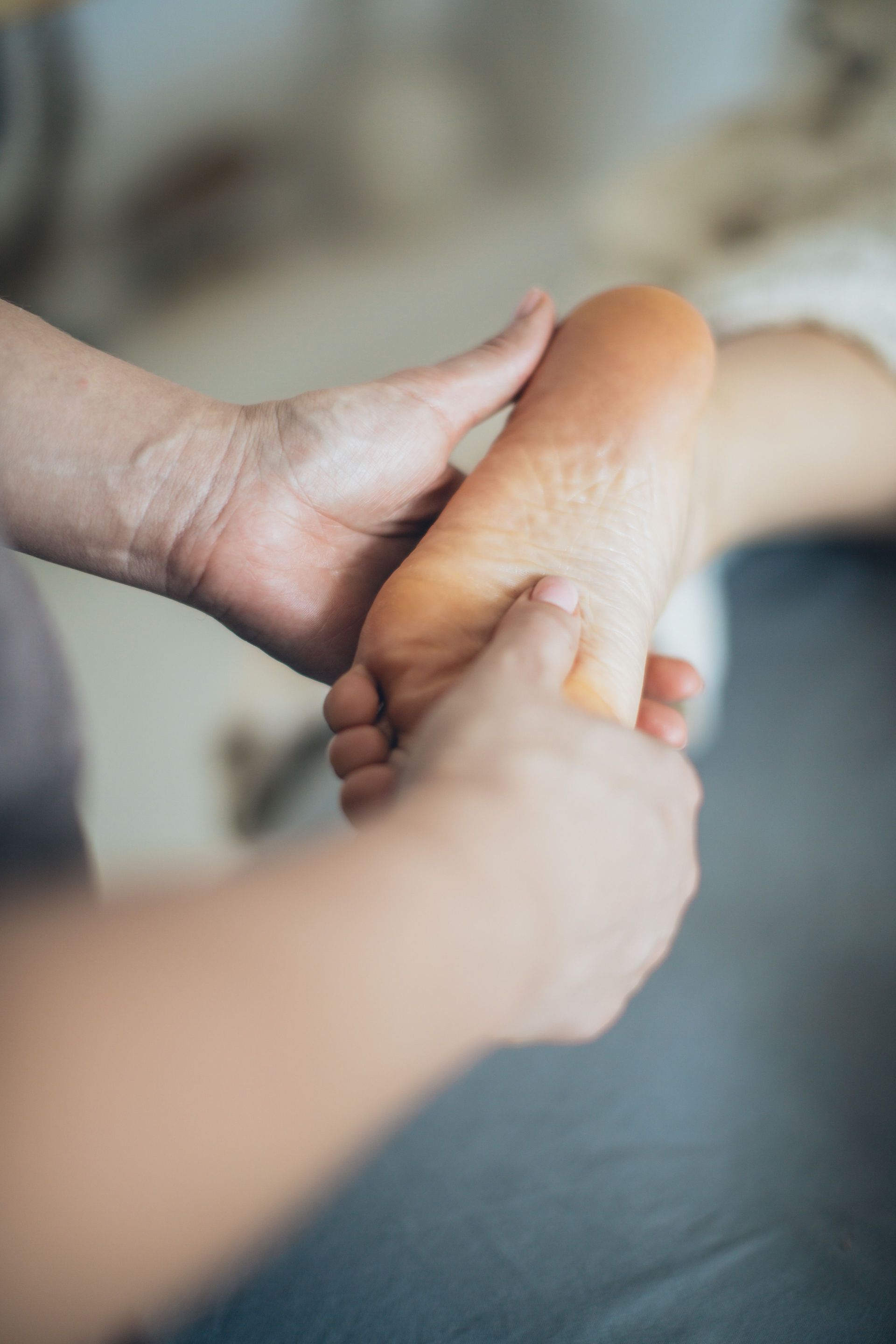 Hands massaging a person’s foot on a soft surface