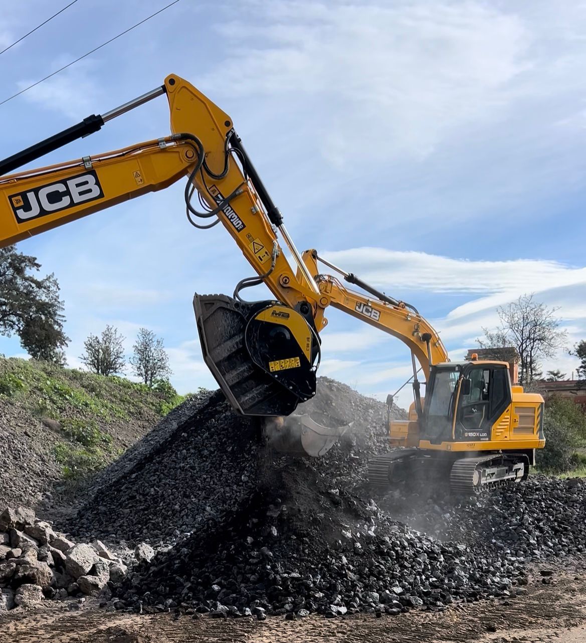 Un escavatore Hitachi arancione demolisce un edificio; macerie e detriti sul terreno.