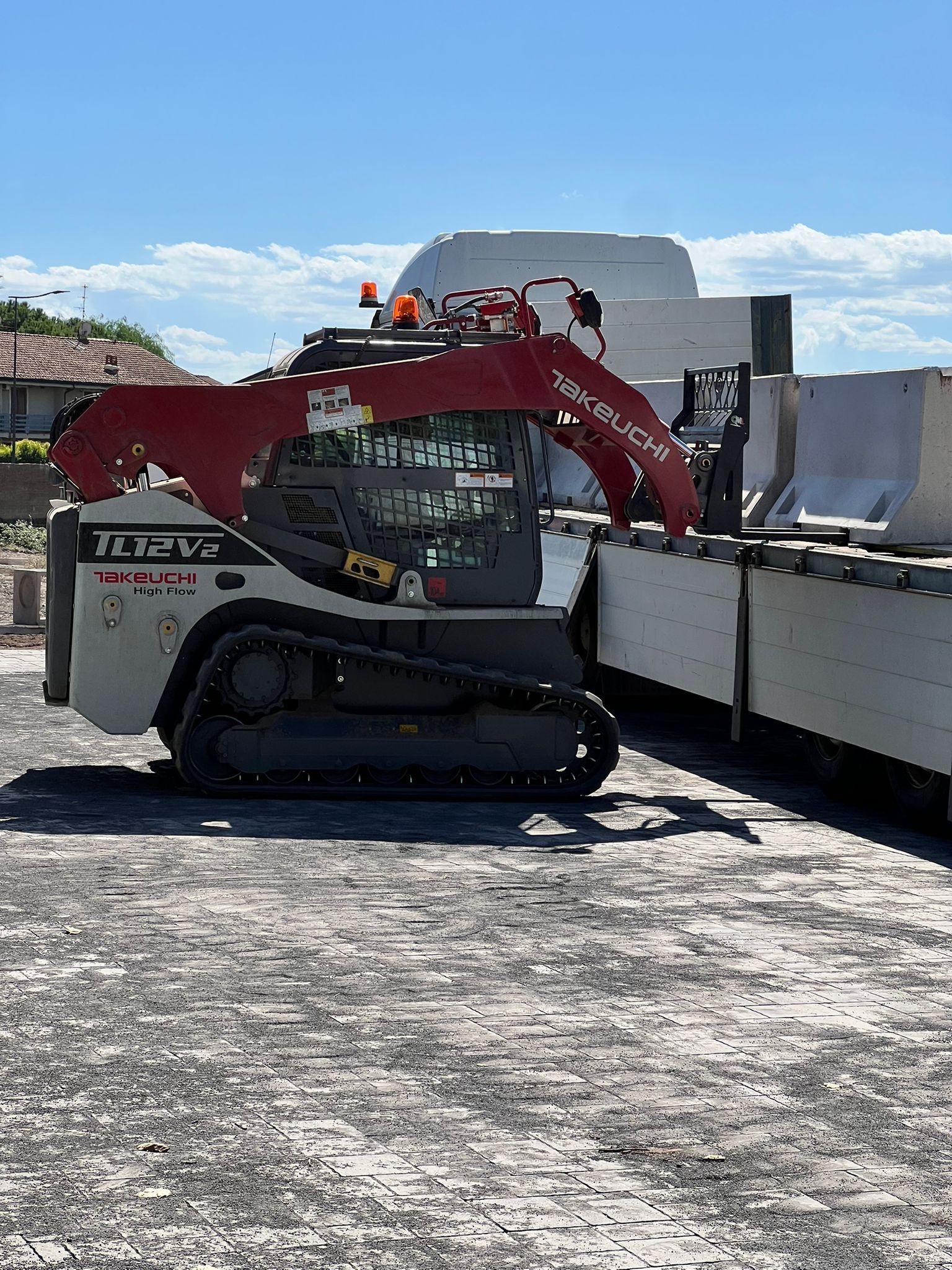 Sollevatore telescopico rosso che solleva materiali in un cantiere edile; edificio in costruzione con legno e cemento.