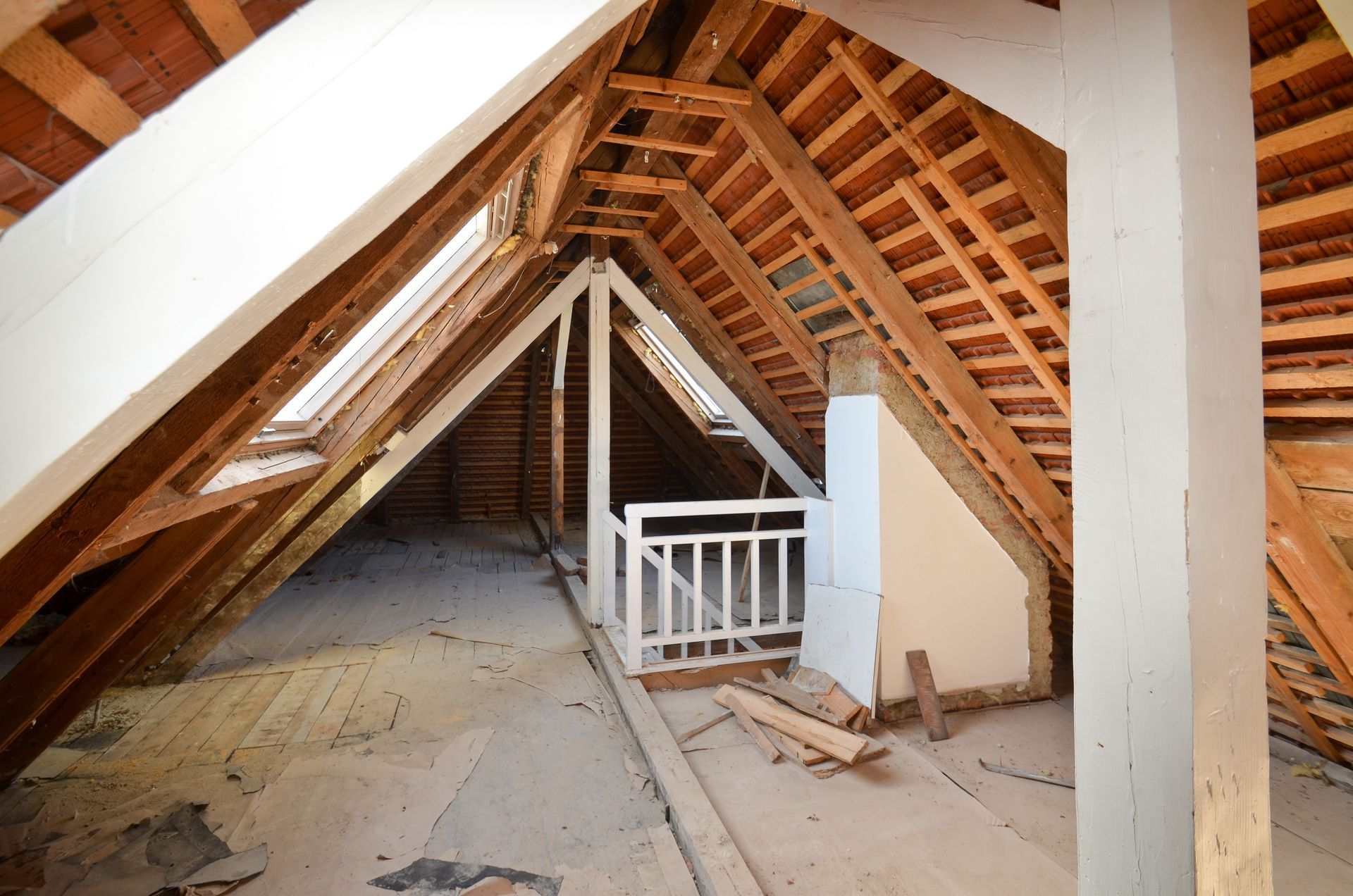Dachgeschoss-Innenraum mit Holzbalken, Oberlichtern und einem kleinen weißen Geländer.