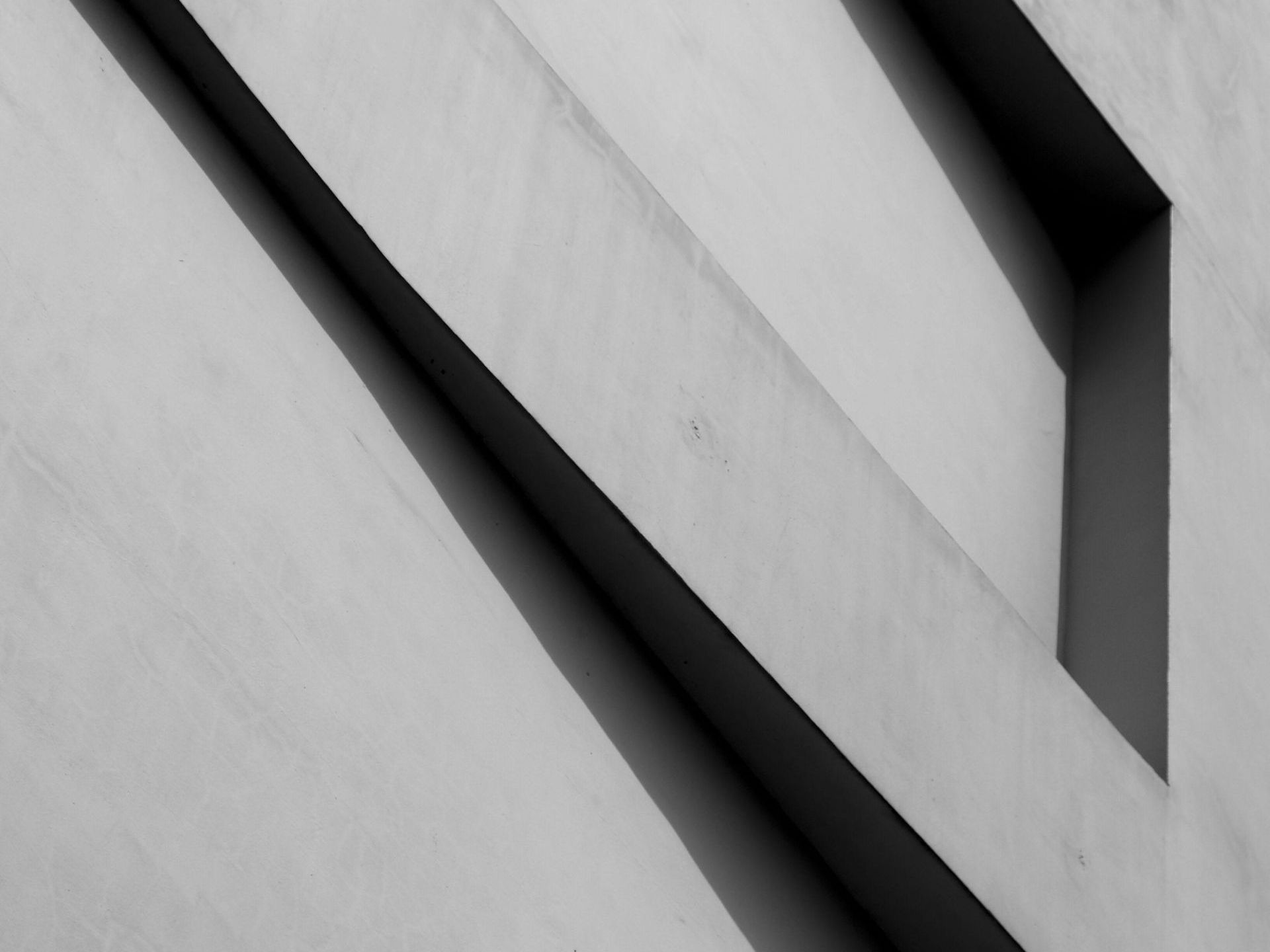 Abstraktes architektonisches Detail. Abgewinkelte Linien erzeugen Schatten und geometrische Formen in Graustufen.