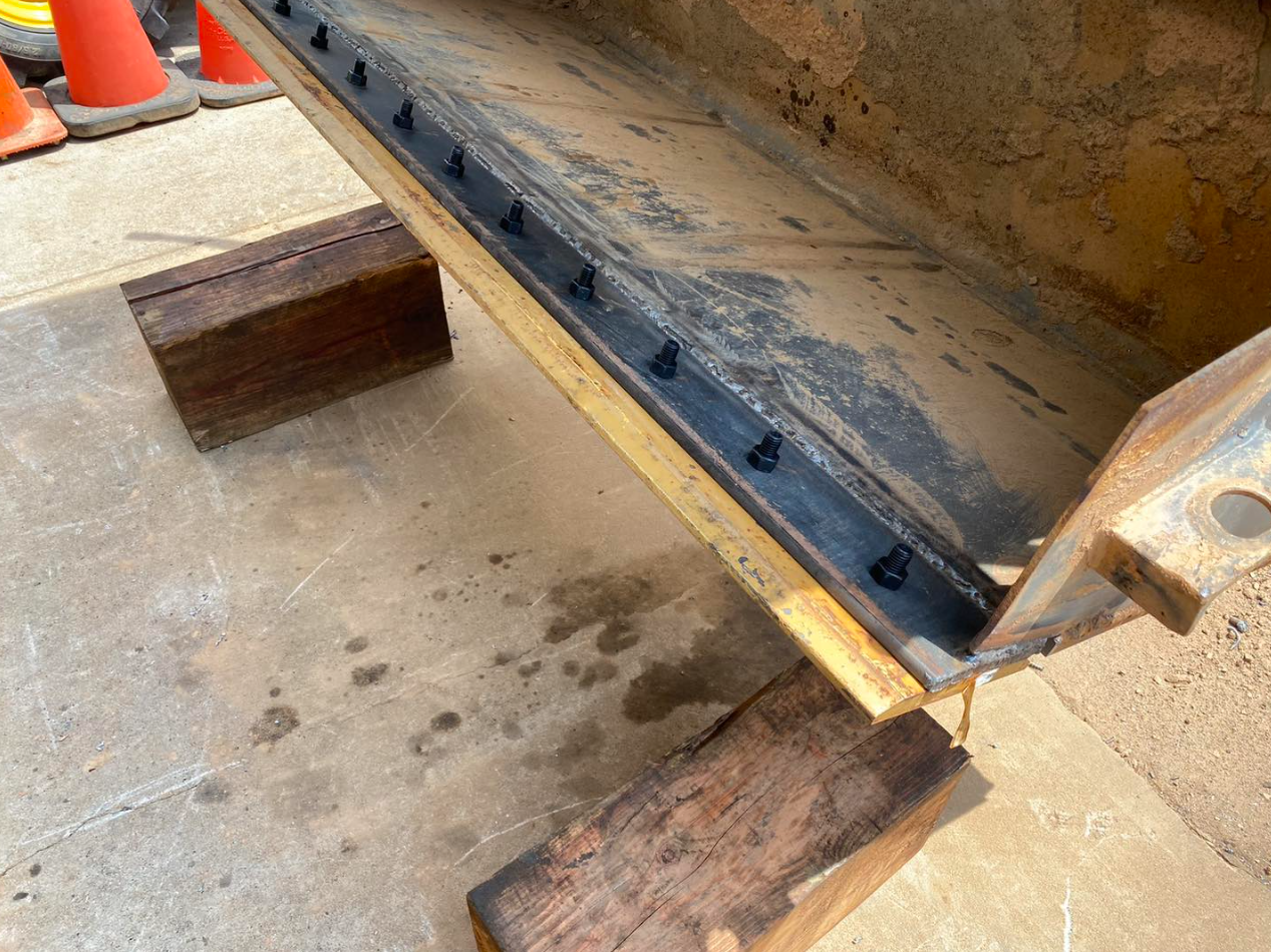 A piece of metal is sitting on top of a wooden block.