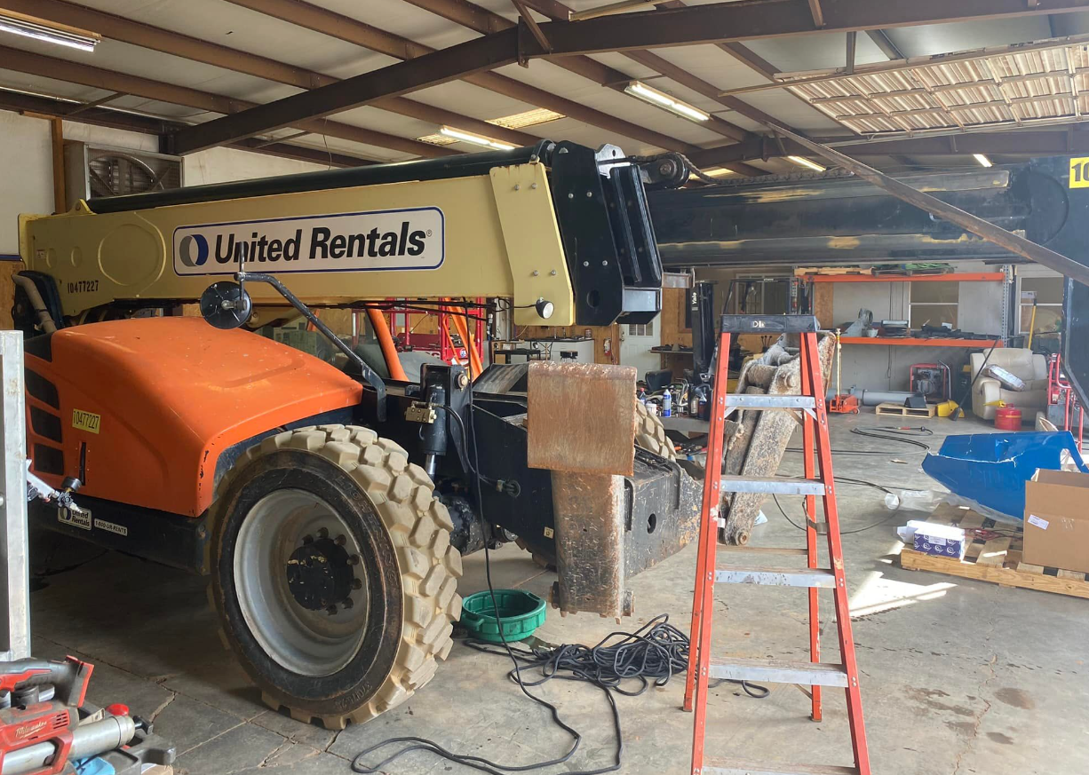 A tractor is sitting in a garage next to a ladder.