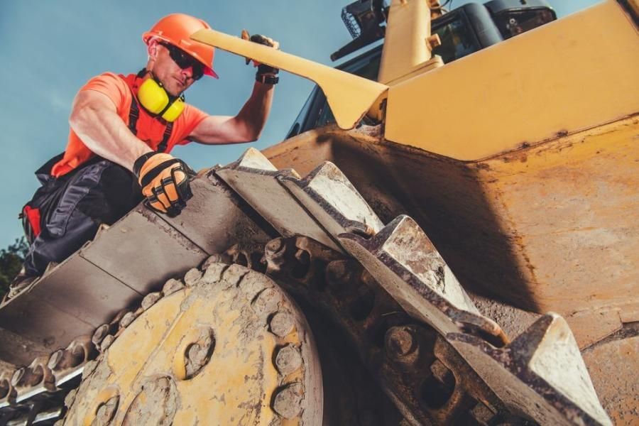 Construction equipment: yellow excavator, orange machinery, and yellow loader outdoors.