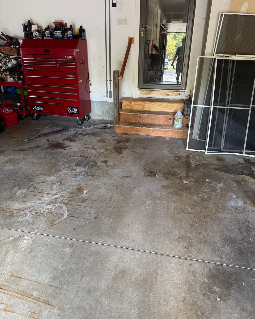 Garage interior with red tool chest, mirror, and stacked windows near a doorway.