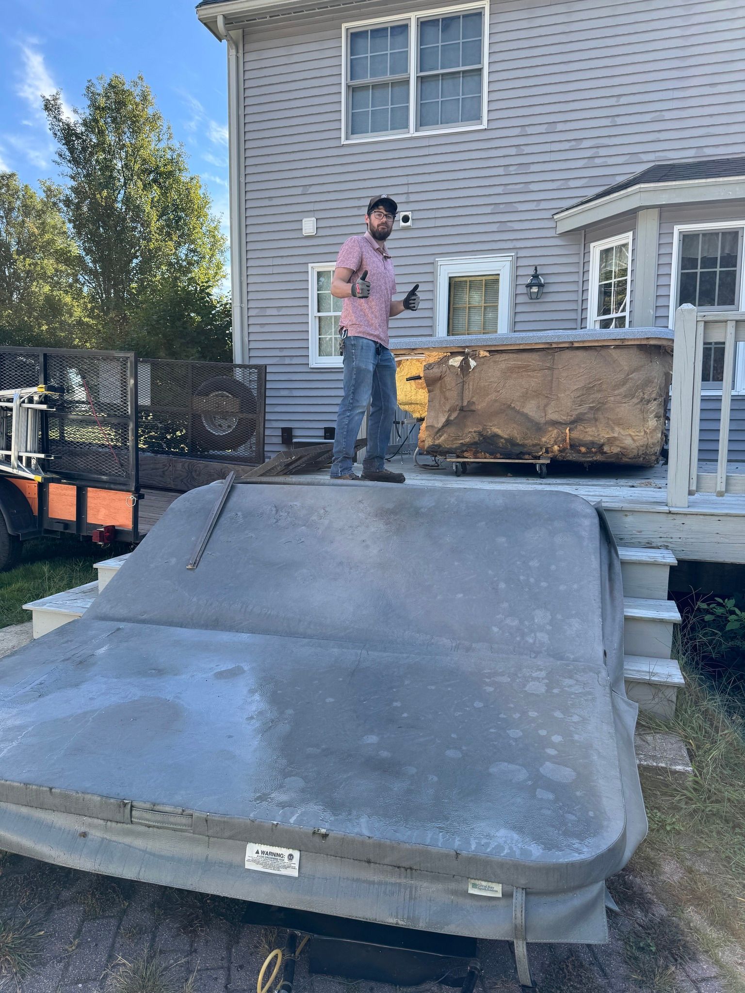 Person standing beside a large mattress on a concrete ramp behind a house