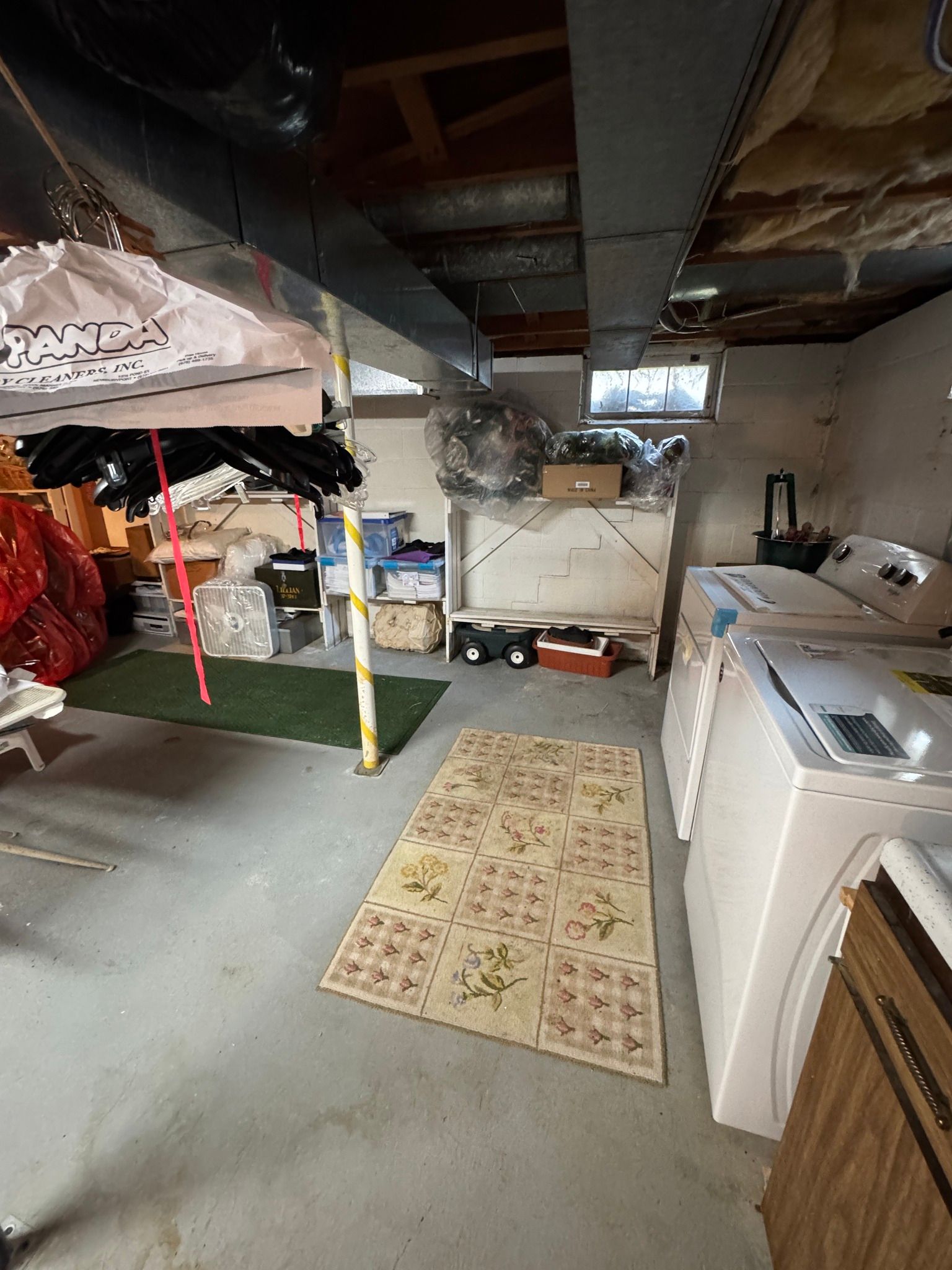 Basement laundry room with washer, dryer, rug, and exposed ceiling beams