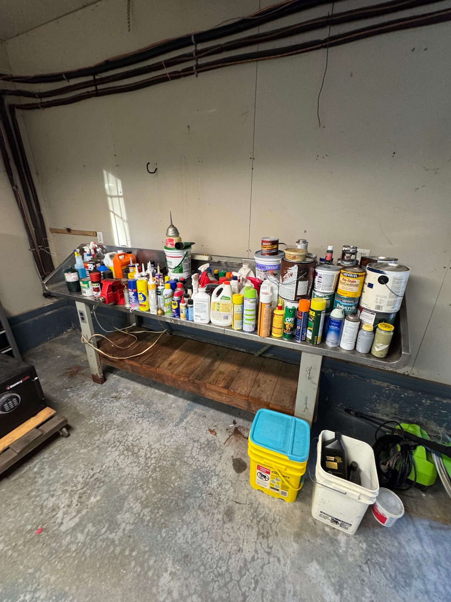 Workbench lined with many spray cans and paint supplies in a garage or workshop.