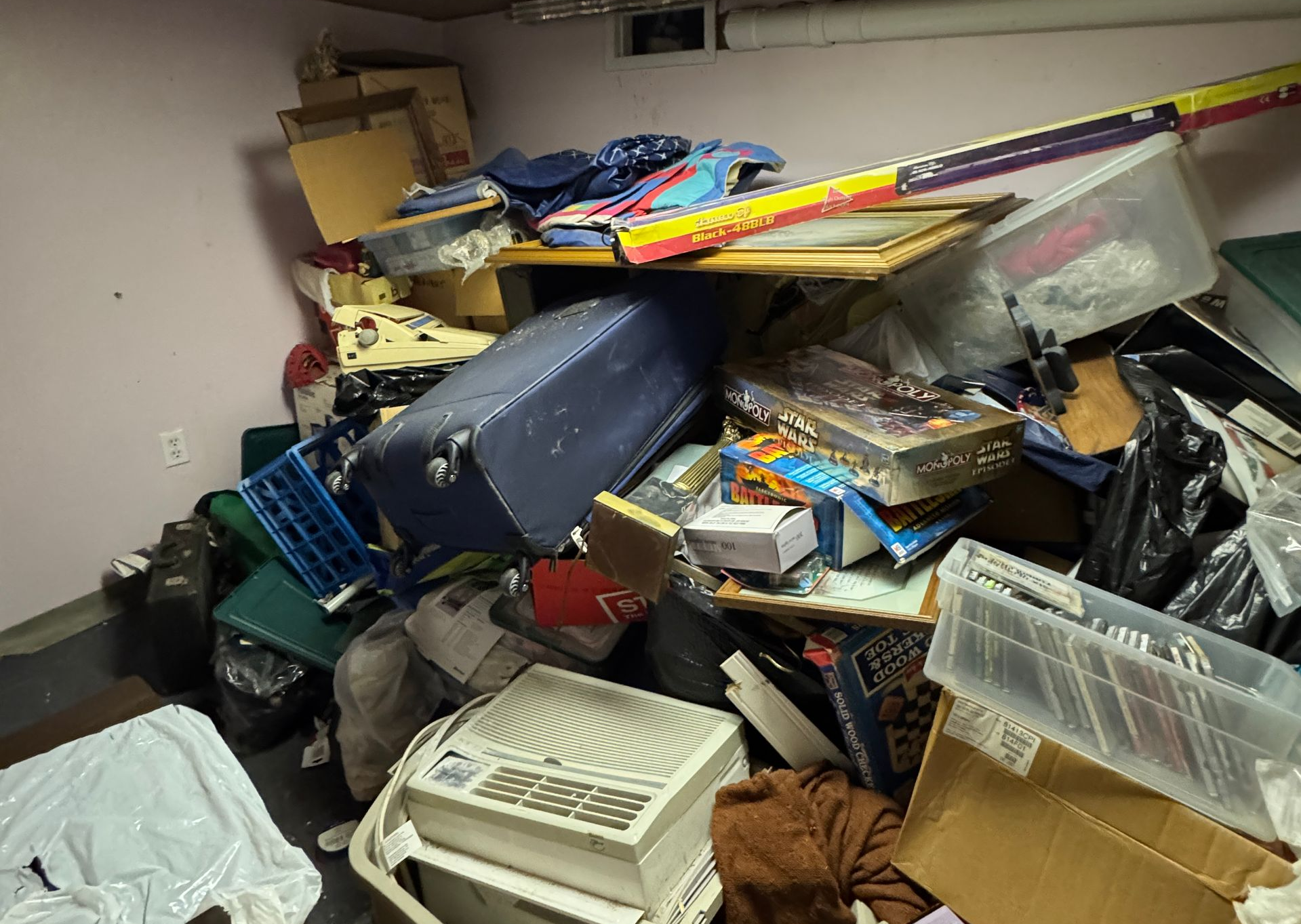 Cluttered storage room piled high with boxes, bags, and assorted household items