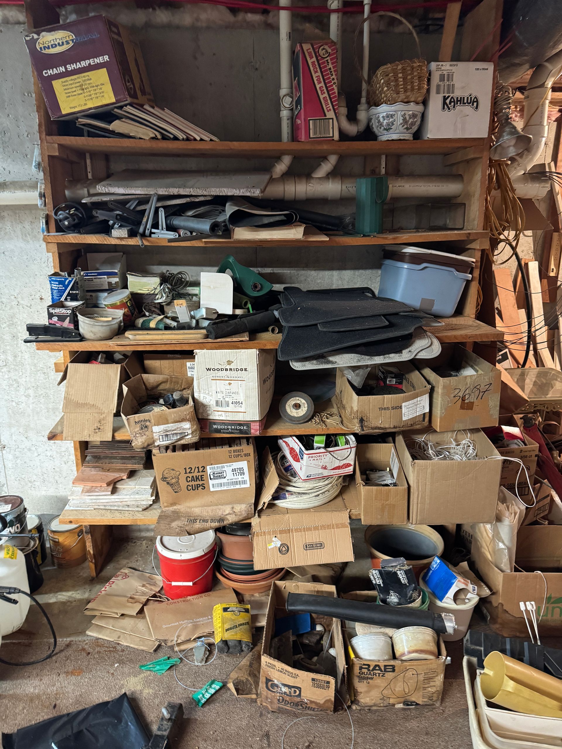 Many boxes and miscellaneous items stacked on multiple shelves in a basement.