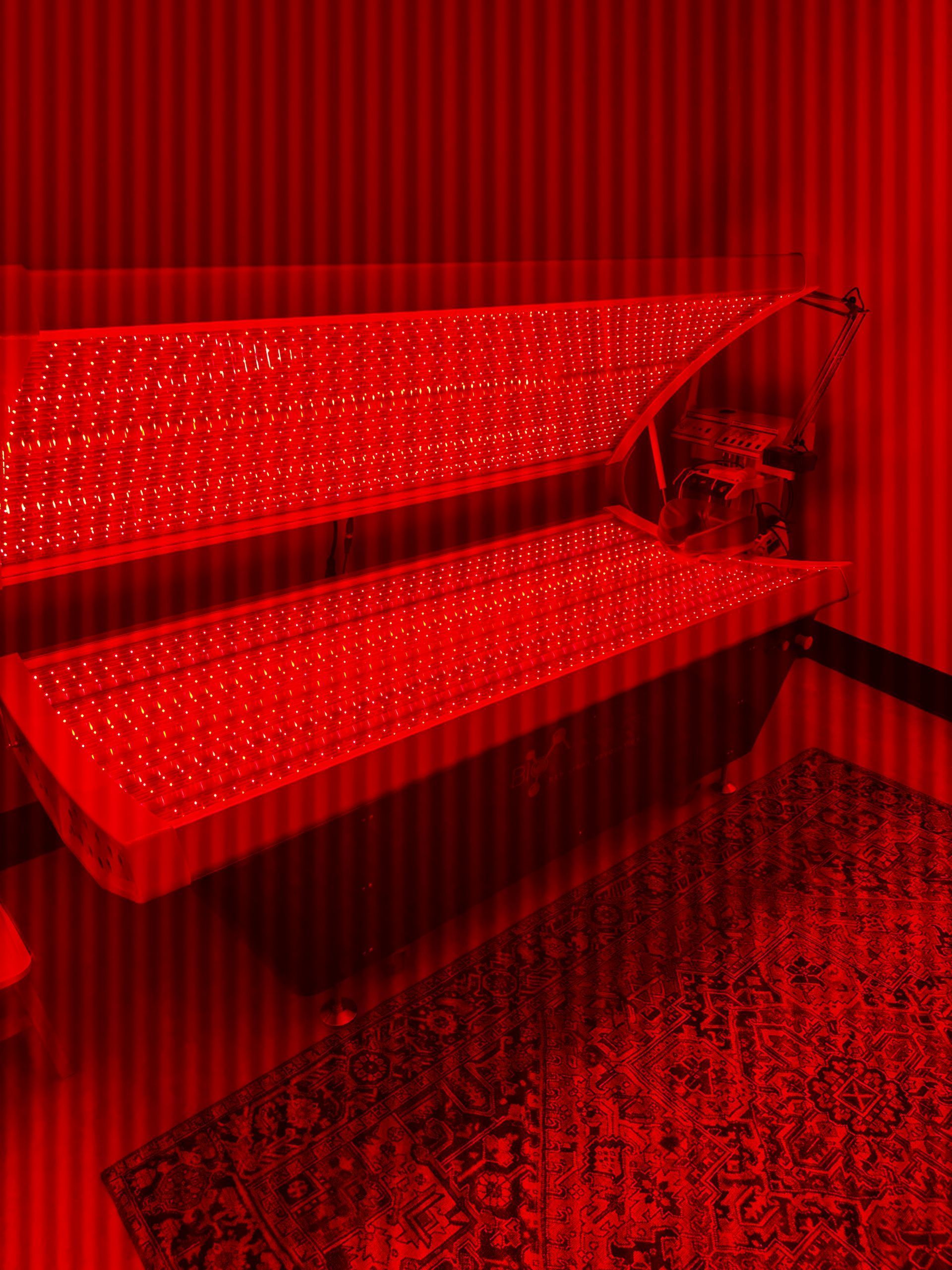 Red-lit bedroom with a bunk bed, patterned bedding, and a carpeted floor