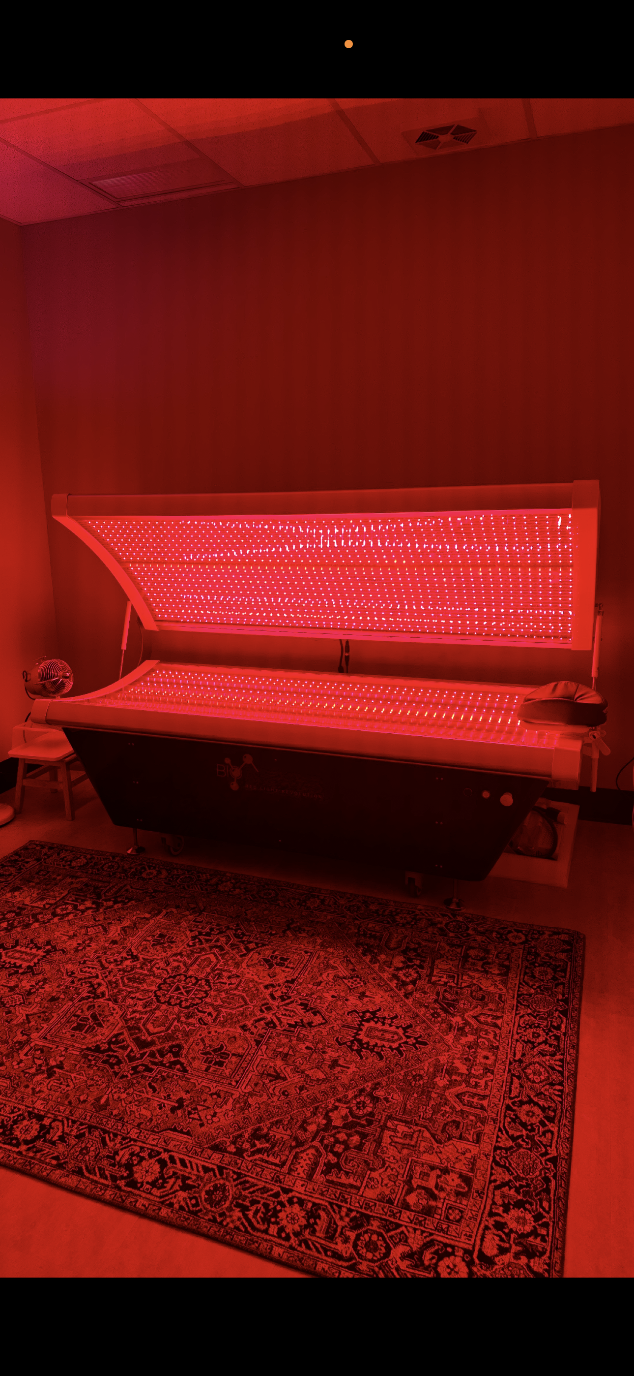 Red-lit room with a large illuminated keyboard piano against a wall and patterned rug on the floor.