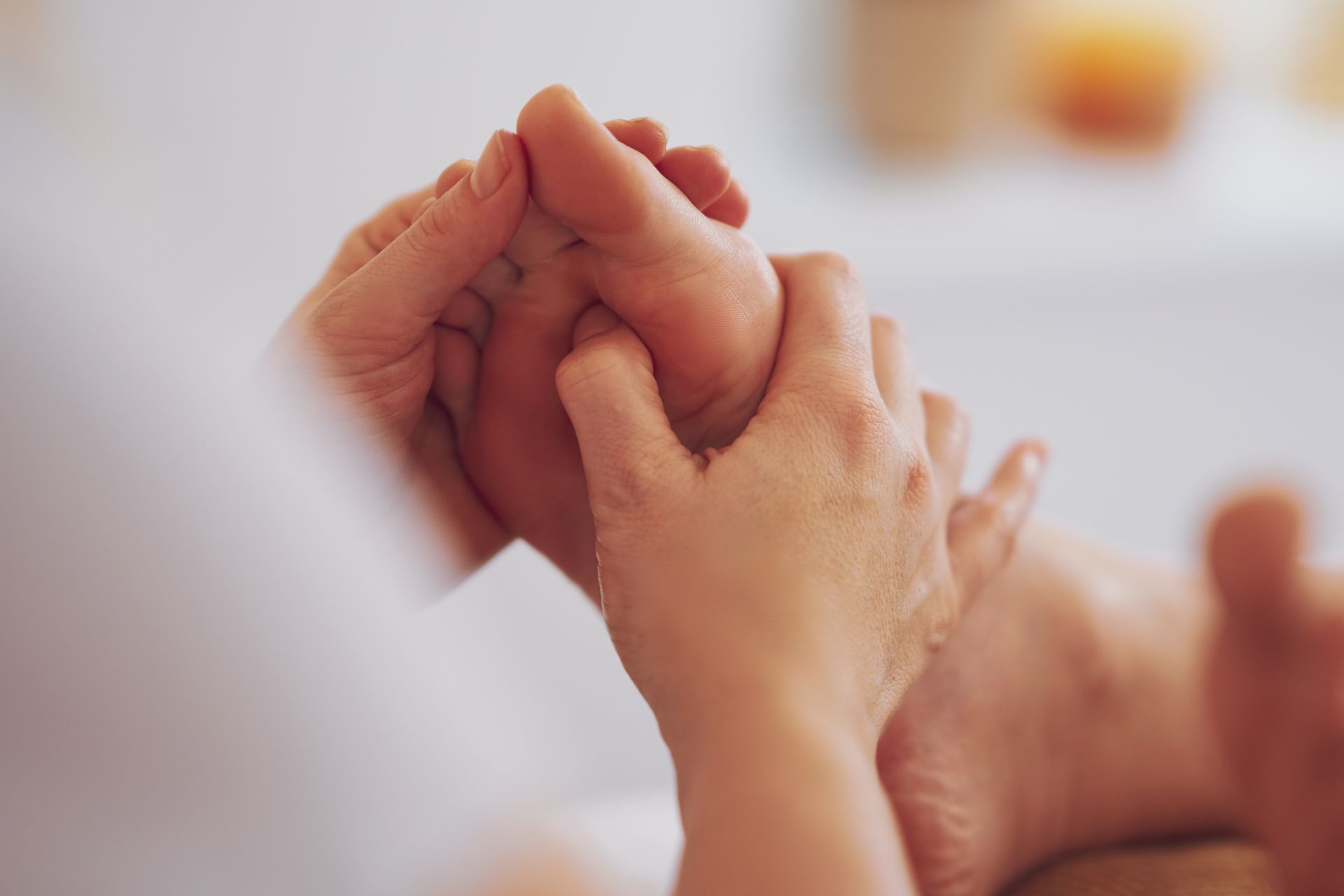 Hands gently holding a baby’s tiny hand in a soft, warm-toned close-up