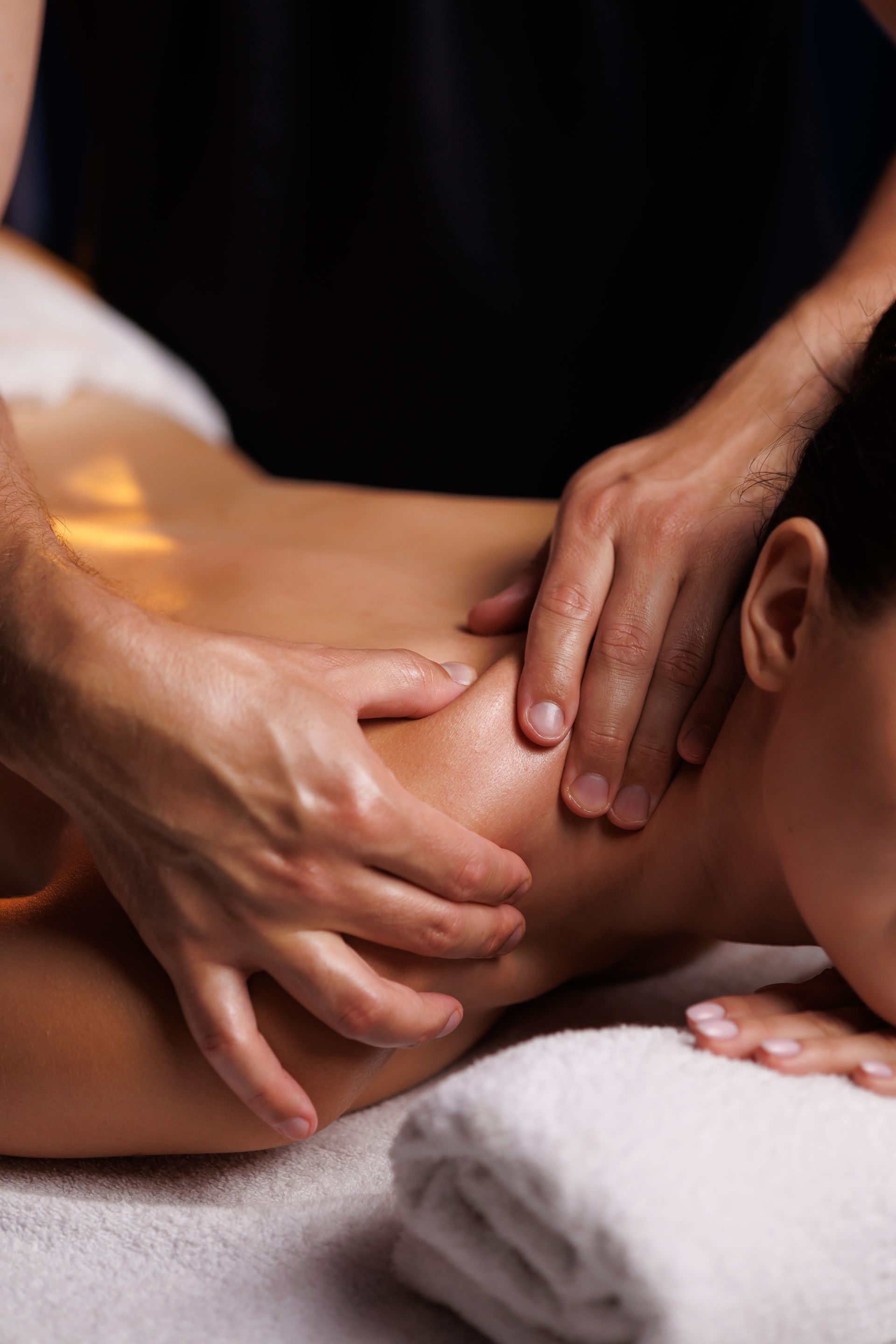 Massage therapist kneading a person's back with hands in a spa setting