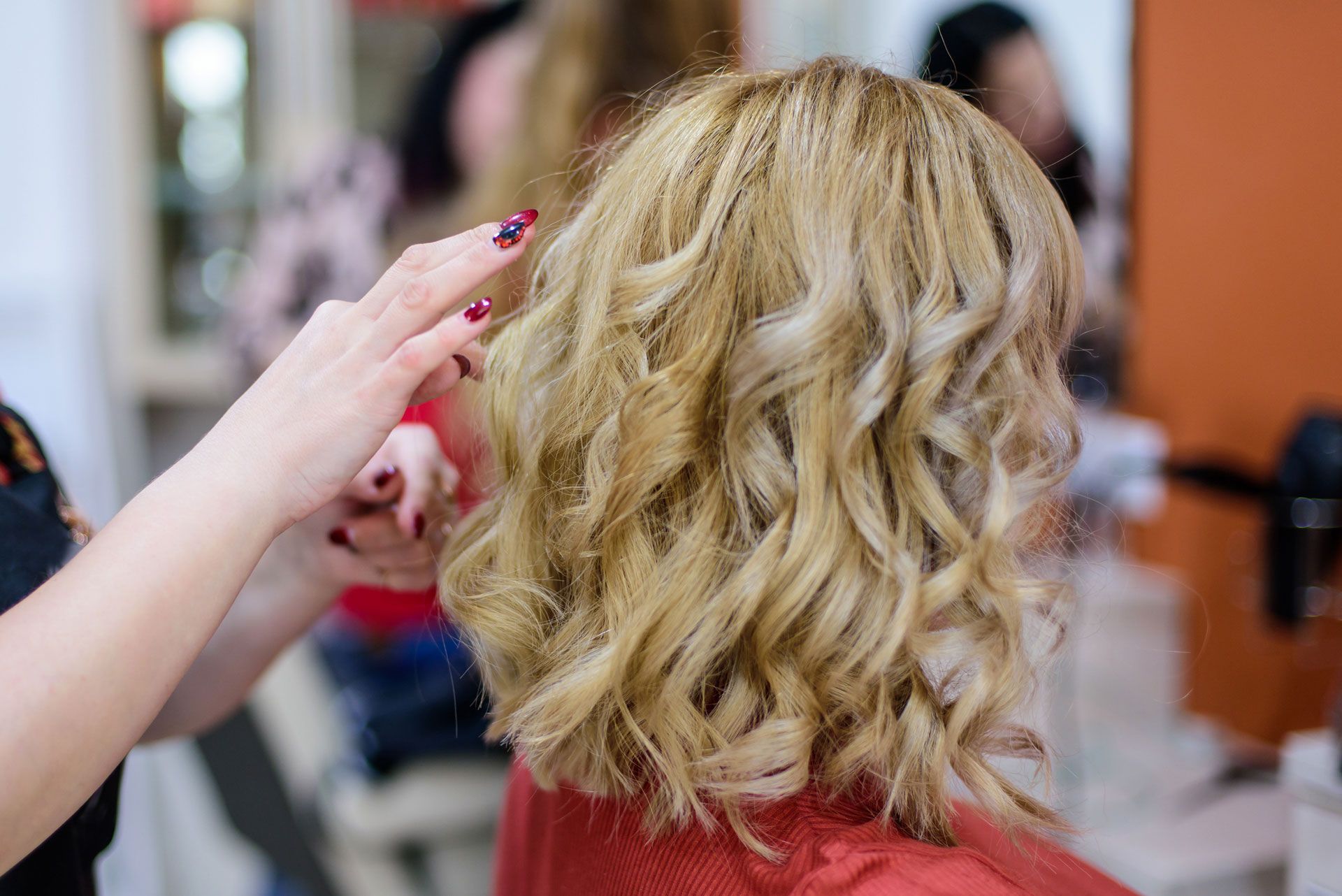 Stylist curling short blonde hair in a salon with a curling iron