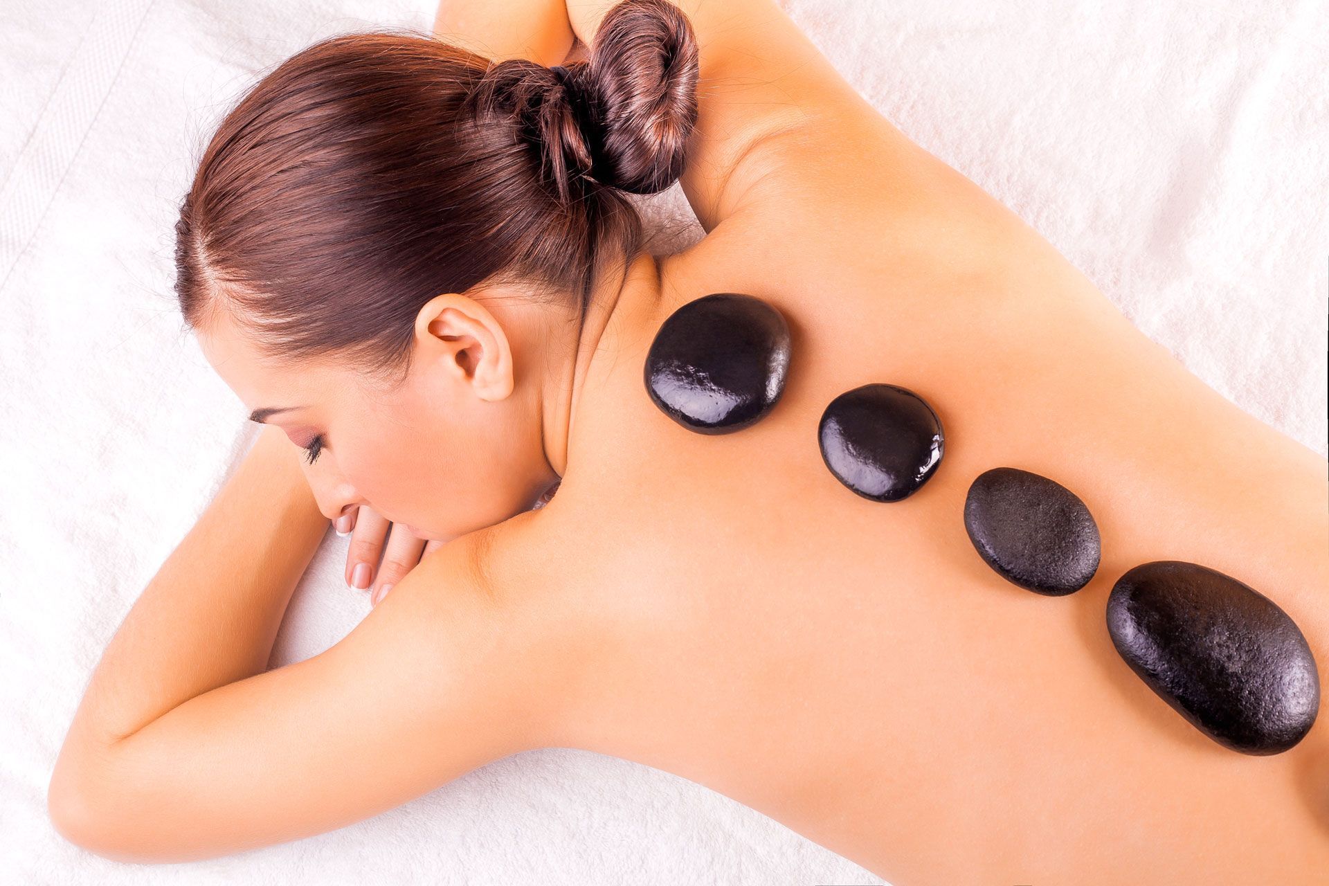 Woman receiving a hot stone massage on her back and shoulders