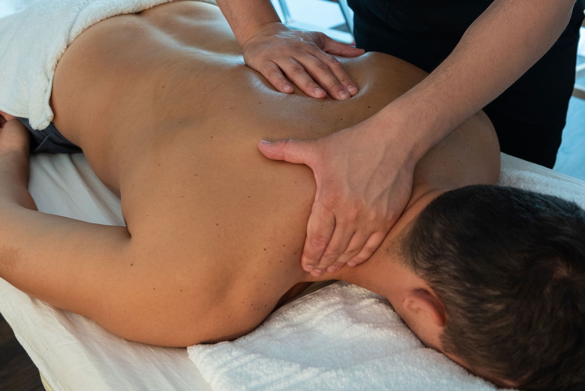 Therapist giving a back massage to a person lying face down on a table
