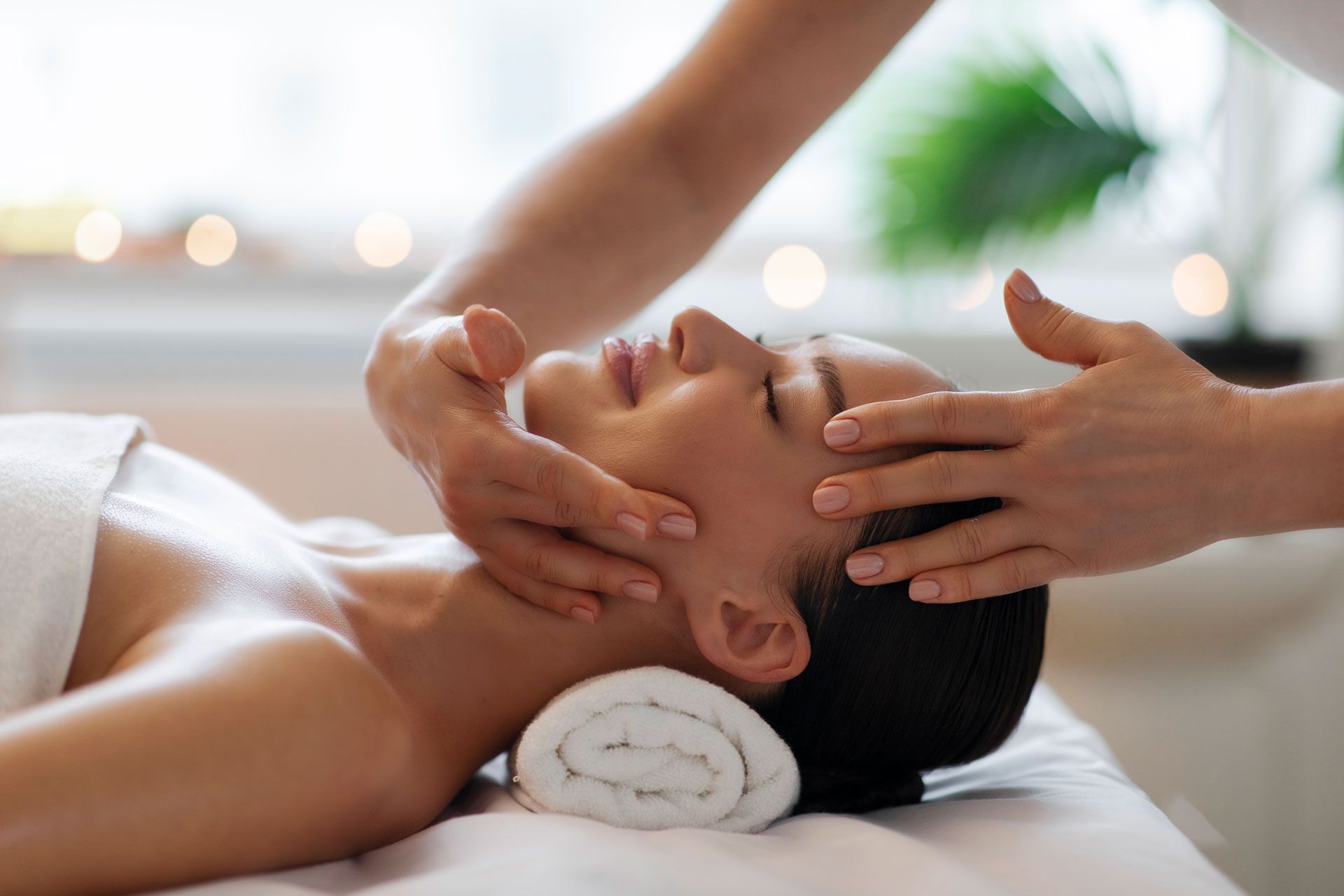 Facial spa massage on a client lying on a treatment table with eyes closed