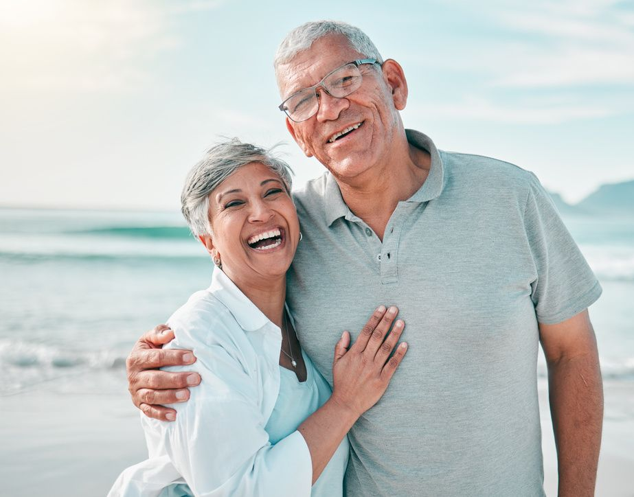 Smiling couple embracing on a beach with ocean waves in the background