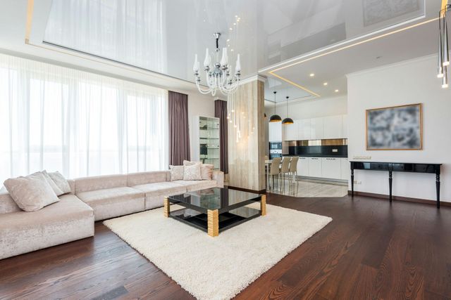 A modern, open-concept living room with a large beige sectional, black glass coffee table, and dark wood floors.