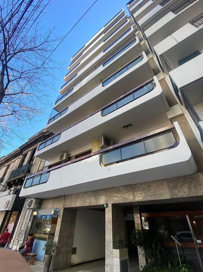 Edificio moderno con paredes de cristal y palmeras al frente; día soleado.