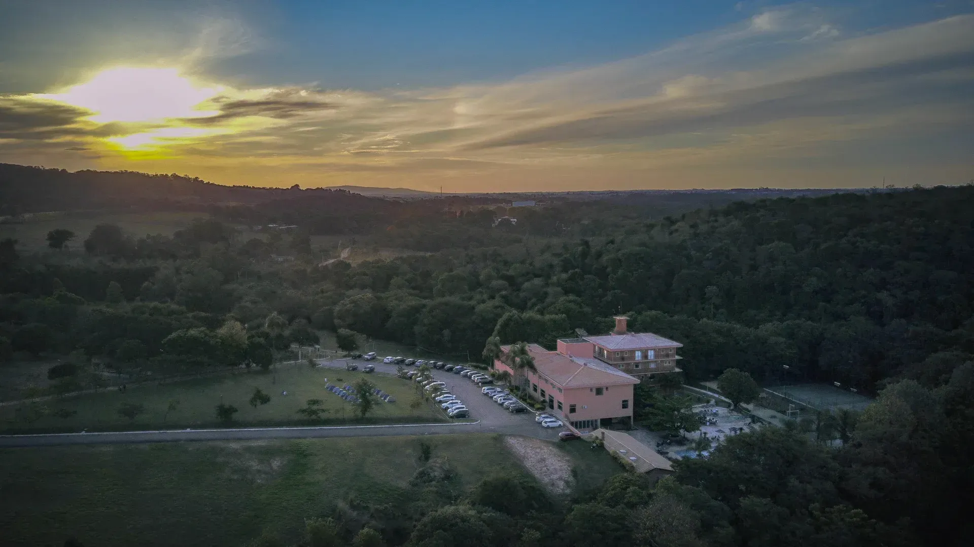 uma vista aérea de uma casa no meio de uma floresta ao pôr do sol.