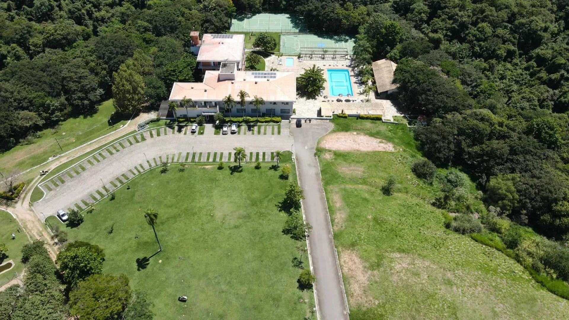 uma vista aérea de uma grande casa cercada por árvores e uma piscina.