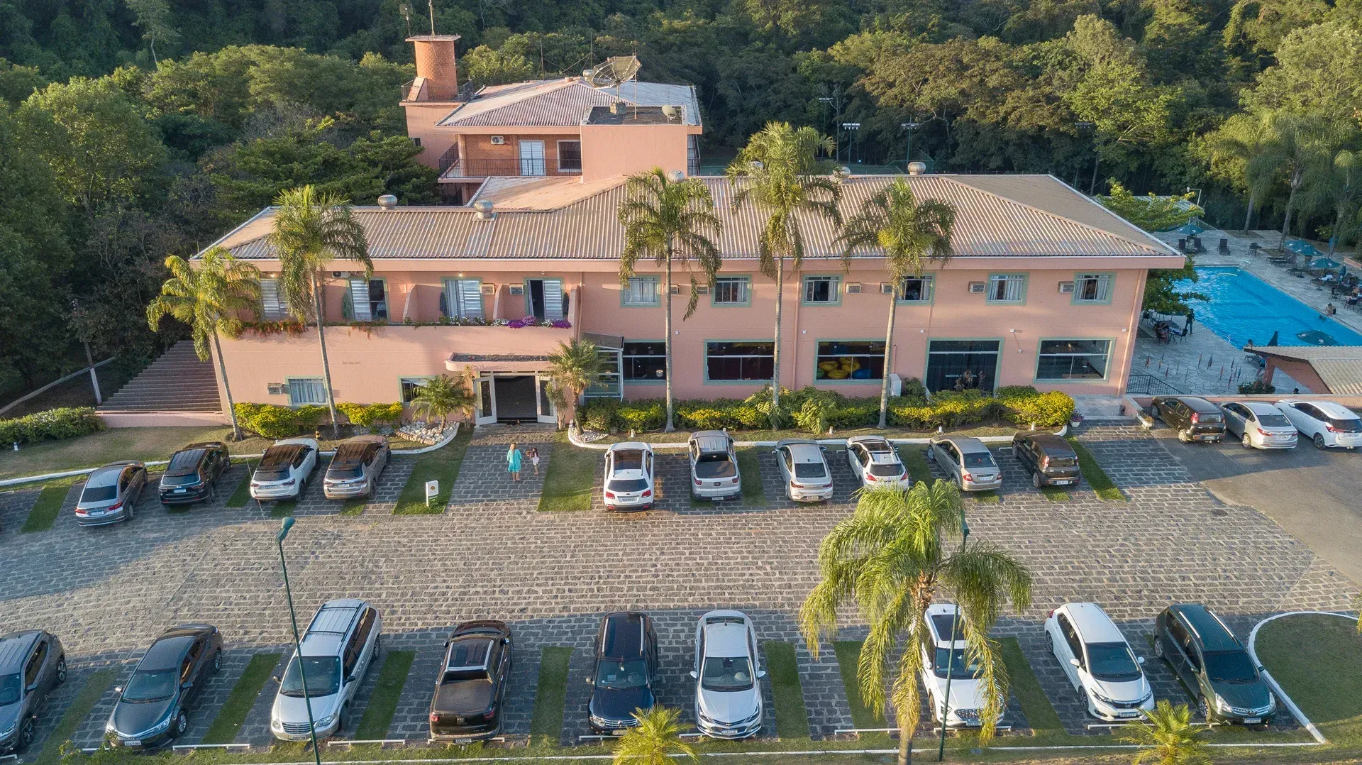 uma vista aérea de um grande edifício com muitos carros estacionados em frente.