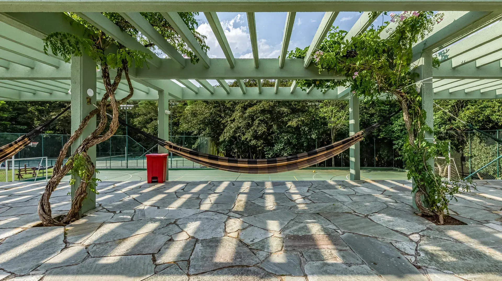 uma rede está pendurada sob uma pérgola em um parque.