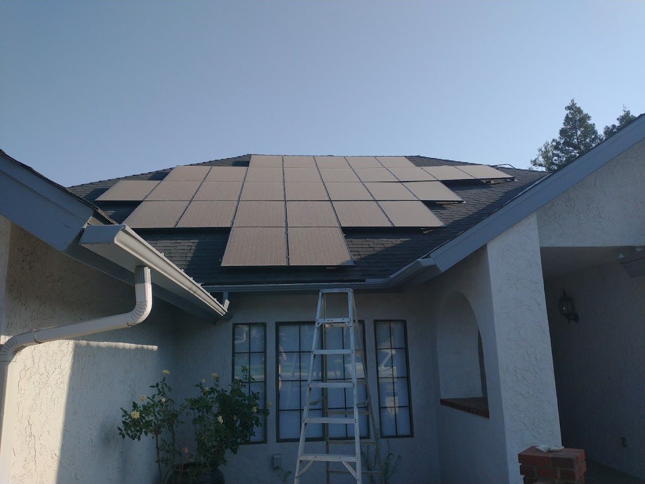 A ladder rests against a suburban home under a roof partially covered by solar panels.