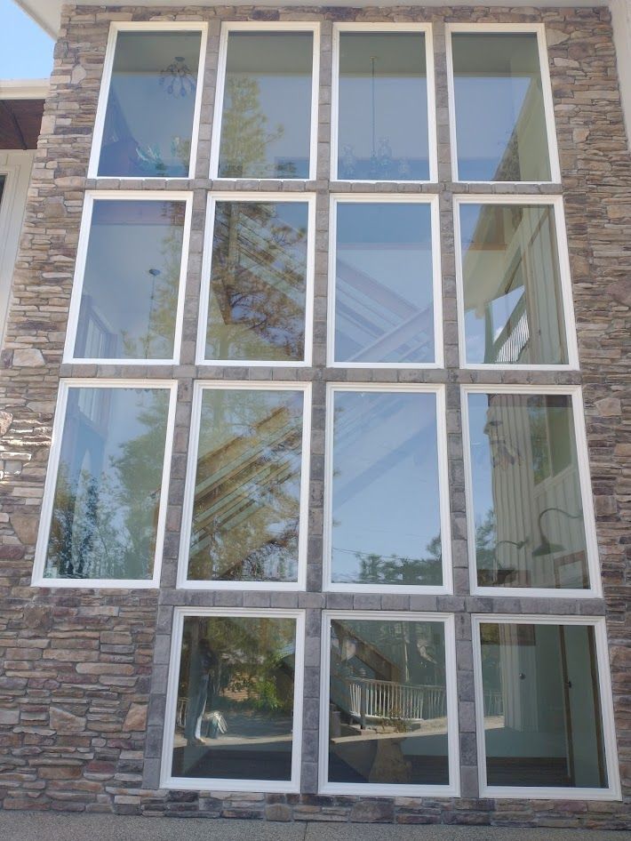 A stone-faced wall featuring a large, symmetrical grid of fifteen rectangular windows with white frames.