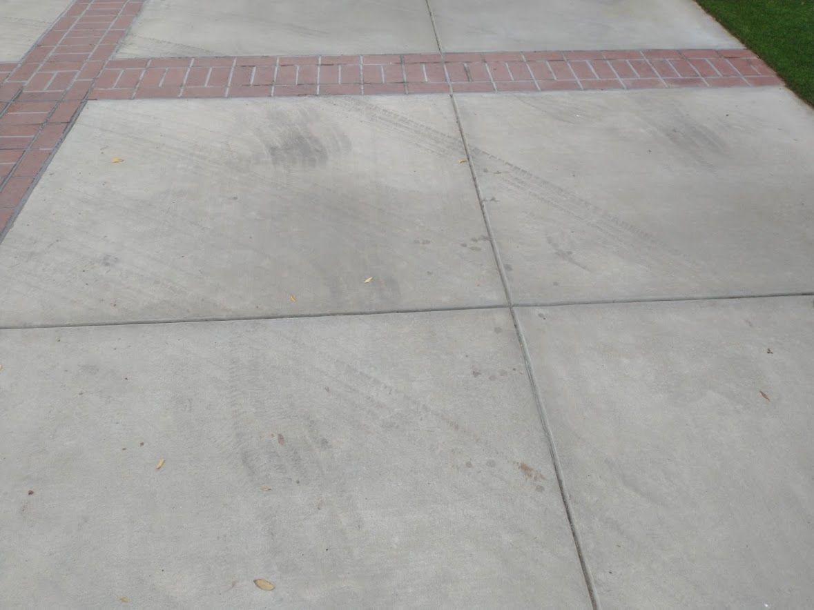 A concrete walkway with grid-patterned sections accented by decorative red brick trim borders.