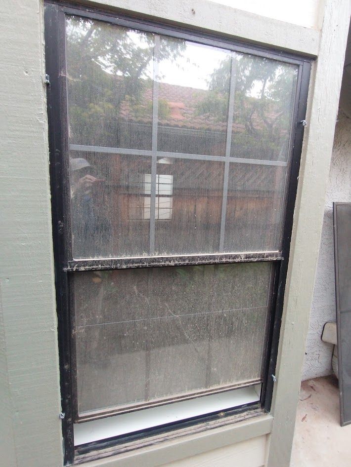 A single-hung window with a black metal frame, divided into six panes on top and a clear glass panel on bottom.