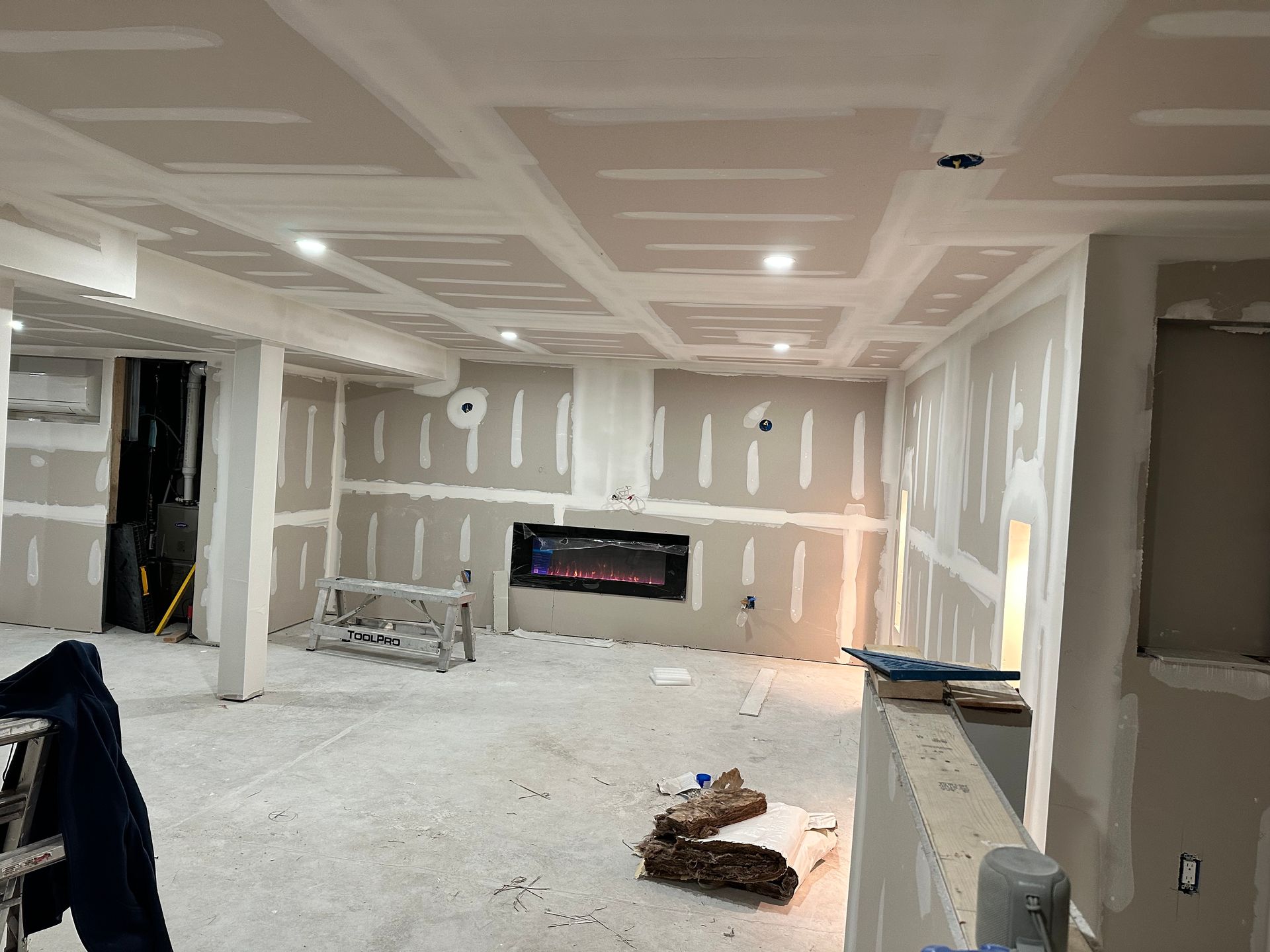 Living-room renovation with coffered ceiling details and unfinished walls around a fireplace