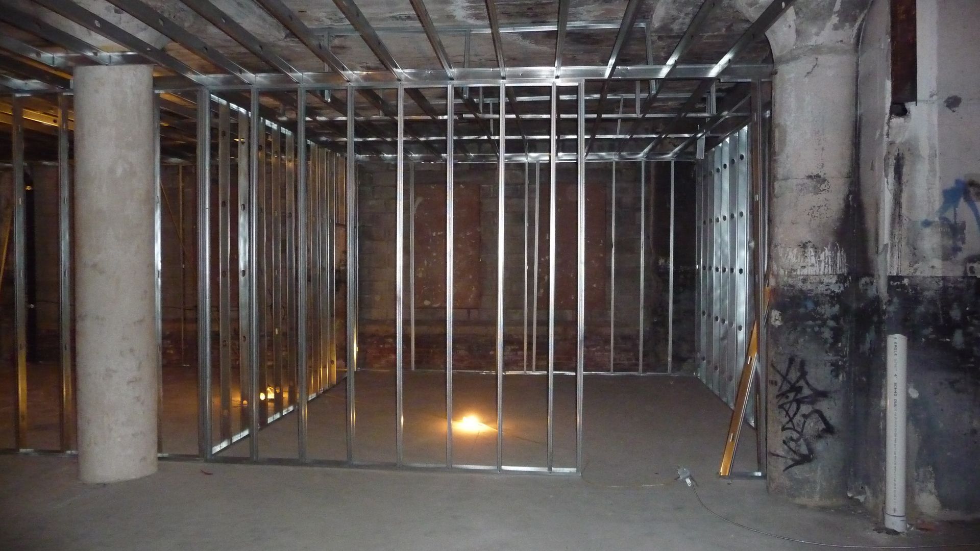 Metal stud wall framing and ceiling channels within an unfinished concrete interior