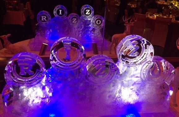 Glowing purple and blue illuminated glass awards or trophies displayed on a table at night