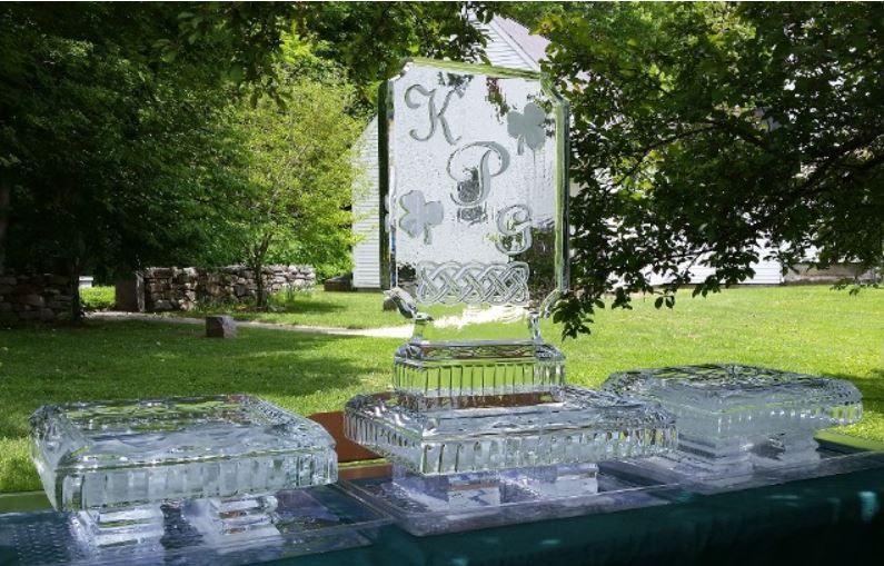Ice sculpture display on a table in a green outdoor garden setting