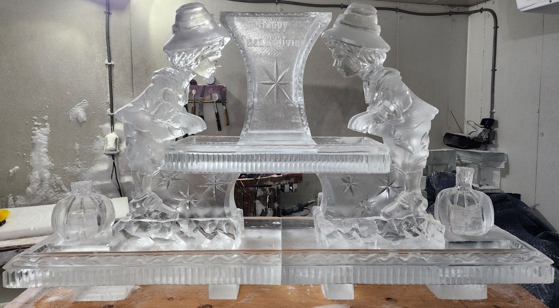 Ice sculpture on a banquet table, featuring a central carved pedestal and decorative frozen figures.