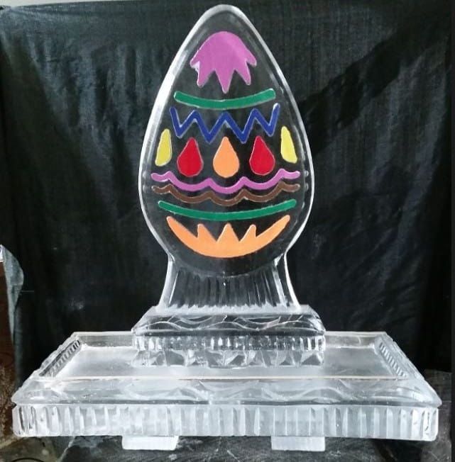 Colorful Easter egg ornament on a clear glass stand against a black background