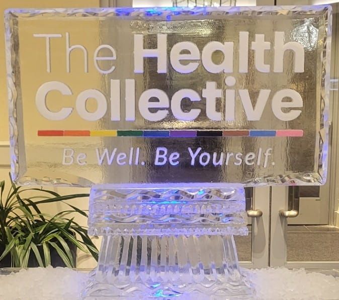 Clear sign reading “The Health Collective” with the slogan “Be Well. Be Yourself.” in a lit display.