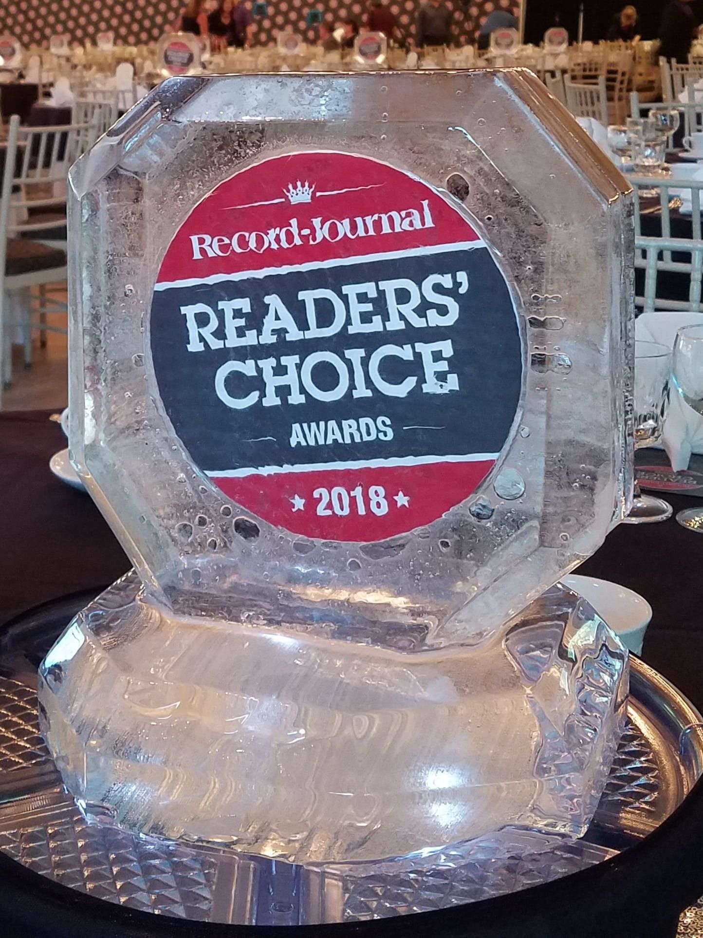 Clear glass award engraved “Record-Journal Readers’ Choice Awards 2018” on a table at an event banquet.